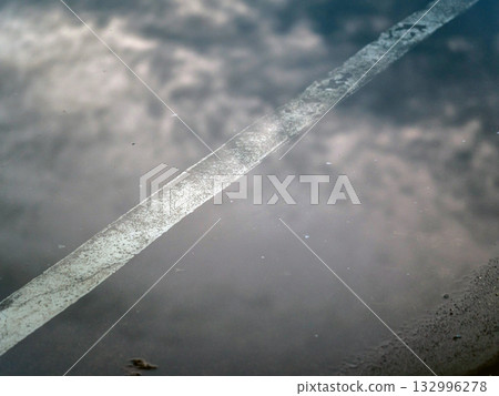 The reflection of the clouds and sky on the flood puddle on the road The reflection of the clouds and sky on the flood puddle on the road 132996278