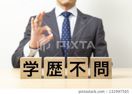 A businessman making an OK pose with a block that says "No educational background required" 132997505