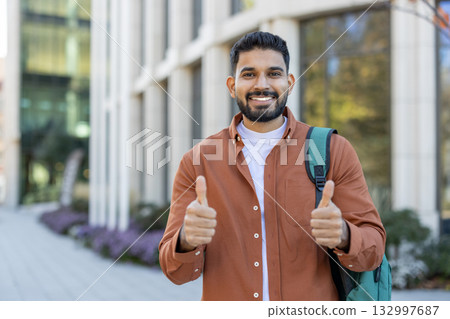 Confident young man wearing casual clothes standing outdoors, giving thumbs up with a bright smile. This positive gesture emphasizes assurance, happiness, and encouragement. Ideal for themes centered Confident young man wearing casual clothes standing outdoors, giving thumbs up with a bright smile. This positive gesture emphasizes assurance, happiness, and encouragement. Ideal for themes centered 132997687