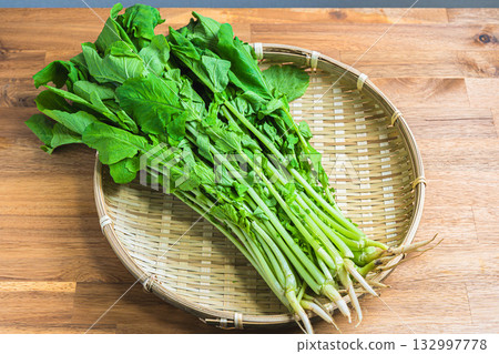葉用蘿蔔：新鮮的蘿蔔葉放在竹籃裡，竹籃放在木桌上。 132997778
