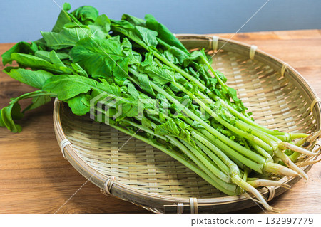 葉用蘿蔔：新鮮的蘿蔔葉放在竹籃裡，竹籃放在木桌上。 132997779