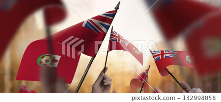 Bermuda flags in their hands on a blurred urban background 132998058