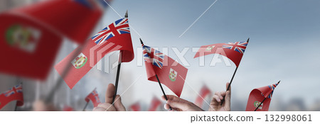 Bermuda flags in their hands on a blurred urban background 132998061