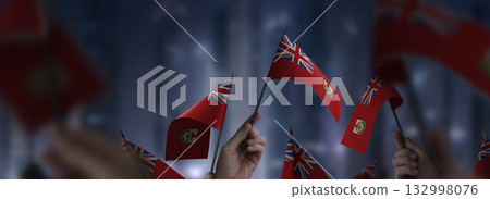 Bermuda flags in their hands on a blurred urban background Bermuda flags in their hands on a blurred urban background 132998076