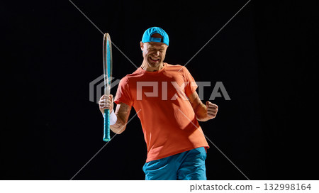 Male tennis player celebrating match win with powerful emotion and raised hands 132998164