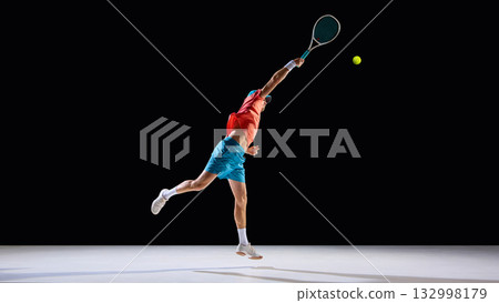 Male tennis player stretching arm to hit ball in midair with full focus 132998179