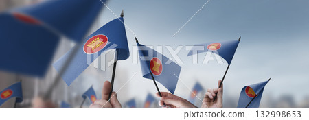 ASEAN flags in their hands on a blurred urban background 132998653