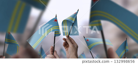 Aruba flags in their hands on a blurred urban background 132998656