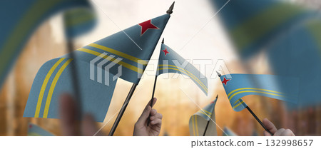 Aruba flags in their hands on a blurred urban background Aruba flags in their hands on a blurred urban background 132998657