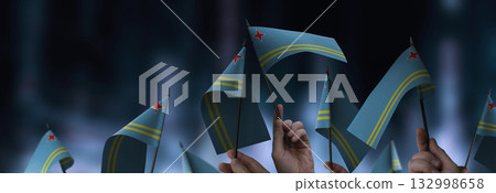 Aruba flags in their hands on a blurred urban background 132998658