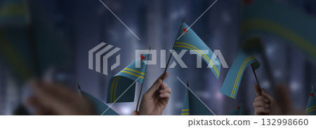 Aruba flags in their hands on a blurred urban background 132998660