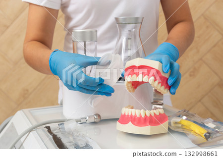 A dental professional operates a mixing machine with a flask, preparing a dental material 132998661