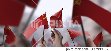 USSR flags in their hands on a blurred urban background USSR flags in their hands on a blurred urban background 132999197