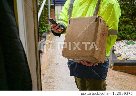 Delivery man at door entrance giving a box to a woman. Online shopping, delivery service 132999375