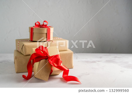 Festive Christmas craft gift boxes with red bows on bright background, Christmas background 132999560