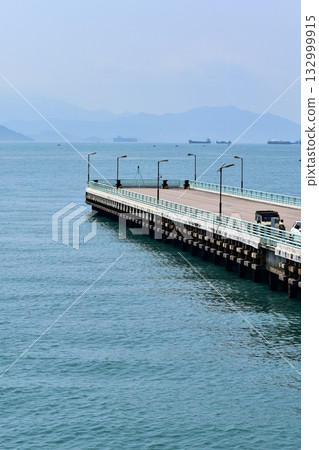 The pier at Tsim Sha Tsui, Hong Kong in the sunny day. Travel and nature scene. Seascape in Hong Kong. Sea background. The pier at Tsim Sha Tsui, Hong Kong in the sunny day. Travel and nature scene. Seascape in Hong Kong. Sea background. 132999915