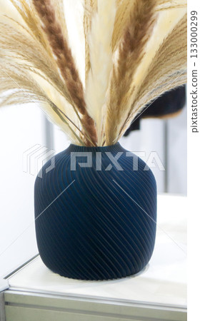 Beautiful dark vase with dried flowers printed on 3D printer on table. Model created by 3D printer from molten plastic. 3D printing technology. New modern additive progressive FDM printing technology Beautiful dark vase with dried flowers printed on 3D printer on table. Model created by 3D printer from molten plastic. 3D printing technology. New modern additive progressive FDM printing technology 133000299