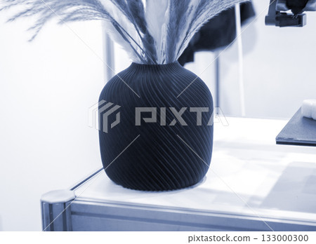Beautiful dark vase with dried flowers printed on 3D printer on table. Model created by 3D printer from molten plastic. 3D printing technology. New modern additive progressive FDM printing technology Beautiful dark vase with dried flowers printed on 3D printer on table. Model created by 3D printer from molten plastic. 3D printing technology. New modern additive progressive FDM printing technology 133000300