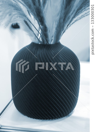 Beautiful dark vase with dried flowers printed on 3D printer on table. Model created by 3D printer from molten plastic. 3D printing technology. New modern additive progressive FDM printing technology Beautiful dark vase with dried flowers printed on 3D printer on table. Model created by 3D printer from molten plastic. 3D printing technology. New modern additive progressive FDM printing technology 133000301