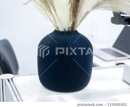 Beautiful dark vase with dried flowers printed on 3D printer on table. Model created by 3D printer from molten plastic. 3D printing technology. New modern additive progressive FDM printing technology Beautiful dark vase with dried flowers printed on 3D printer on table. Model created by 3D printer from molten plastic. 3D printing technology. New modern additive progressive FDM printing technology 133000302