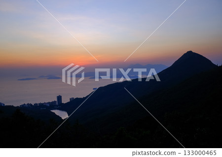The seascape at sunset with ships and cityscape in the background. Sun-rays reflected on the calm sea. Sea background and cityscape. Nature concept. 133000465