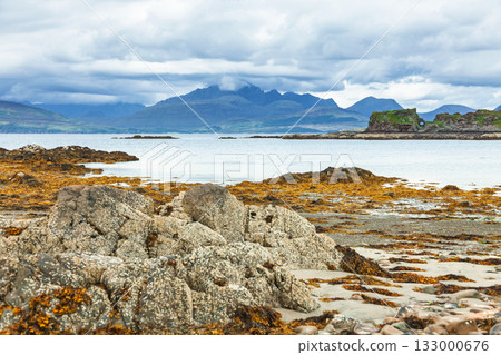Dunscaith Castle ruins and Cuillin mountains seen across rocky shore Isle of Skye Scotland Dunscaith Castle ruins and Cuillin mountains seen across rocky shore Isle of Skye Scotland 133000676