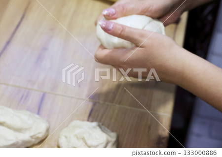 A woman holds a lump of dough in her hands, making preparations for the national Georgian dish, khachapuri, close-up 133000886
