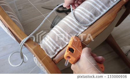 Anonymous person applies glue with glue gun and attaches tape. Antique furniture restoration. Crafts and hobbies. 133000936