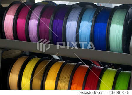 Many spools with multi-colored plastic for 3D printing. Spools with pink, red, burgundy, purple blue plastic wire for 3D printer. Components for 3D printing. Accessories for 3D printer. FDM technology 133001096
