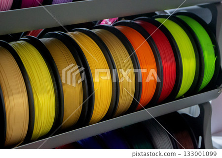 Many spools with multi-colored plastic for 3D printing. Spools with yellow, orange, brown, red green plastic wire for 3D printer. Components for 3D printing. Accessories for 3D printer. FDM technology Many spools with multi-colored plastic for 3D printing. Spools with yellow, orange, brown, red green plastic wire for 3D printer. Components for 3D printing. Accessories for 3D printer. FDM technology 133001099