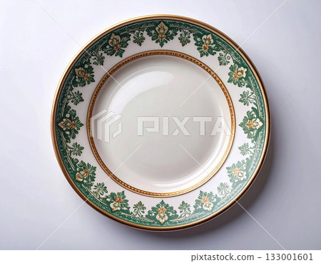 Vintage elegance. Ceramic plate with a green and gold pattern on a white background. Porcelain kitchenware. Close-up. Top view. Vintage elegance. Ceramic plate with a green and gold pattern on a white background. Porcelain kitchenware. Close-up. Top view. 133001601