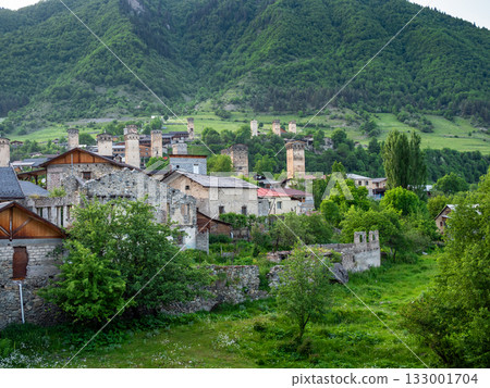 old houses in Mestia town on green mountain slope 133001704