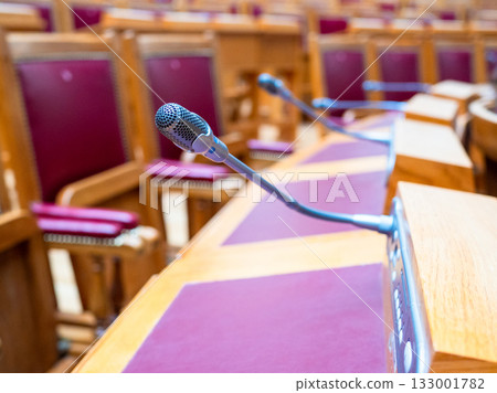 microphone closeup at desks in conference hall 133001782