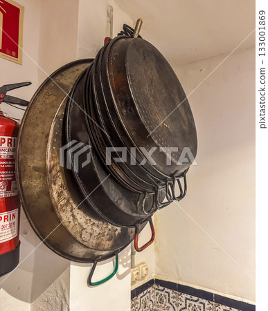 Stack of Old Paella Pans Hanging on Wall in Rustic Spanish Kitchen Stack of Old Paella Pans Hanging on Wall in Rustic Spanish Kitchen 133001869