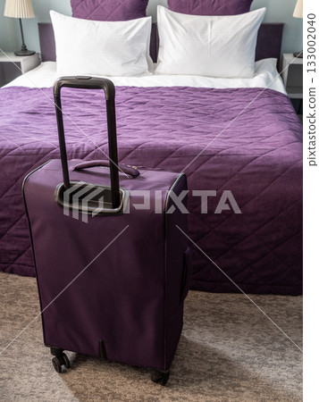 purple suitcase, bed with white and purple linens 133002040