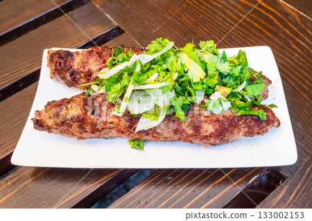 Georgian meat kebab on white plate on wooden table Georgian meat kebab on white plate on wooden table 133002153