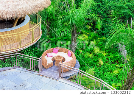 A circular rattan seating area with pink cushions against a backdrop of lush tropical plants in Yanoda Park, Sanya, Hainan, China 133002212
