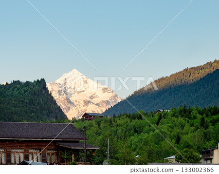 snow-covered mountain peak lit by setting sun 133002366