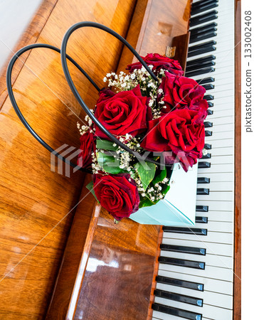 burgundy roses in bag box on keyboard of piano burgundy roses in bag box on keyboard of piano 133002408