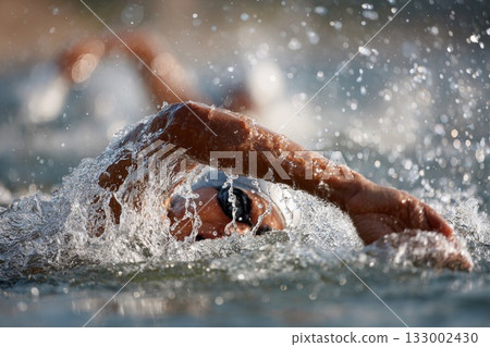 Competitive swimmer in action splashing water during outdoor race showcasing athleticism and determination 133002430