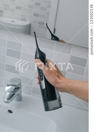 close view of a man lifting an oral irrigator 133002536
