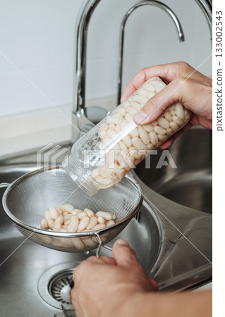 a man pouring white beans into a sieve 133002543