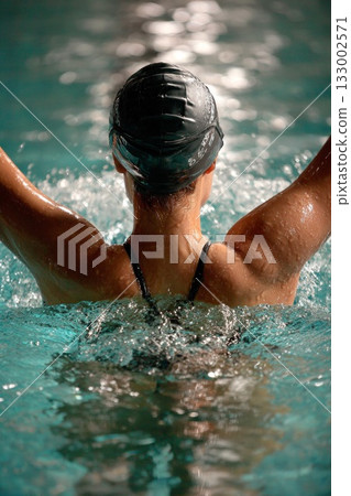 Swimmer preparing for springboard diving with water splashing around in a competitive environment 133002571