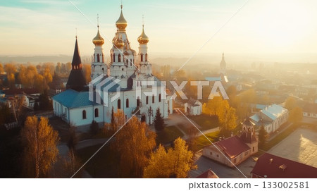 Aerial view of historic church with golden domes surrounded by autumn foliage and village landscape 133002581