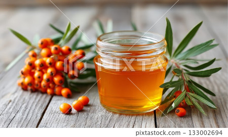 Sea buckthorn oil in glass jar with fresh sea buckthorn berries and leaves on wooden surface 133002694