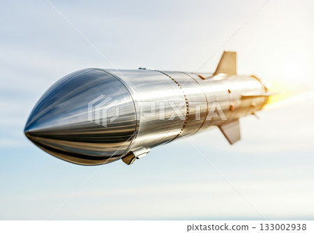 Rocket launching into the sky with bright flames and metallic surface reflecting sunlight 133002938