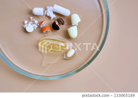 Broken pills and supplements dissolving in petri dish 133003189