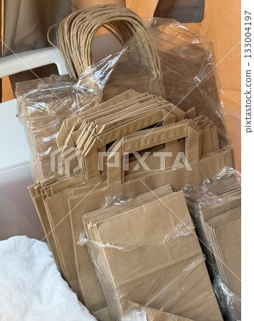Brown paper bags neatly stacked with rustic twine handles, viewed from above in a casual setting 133004197