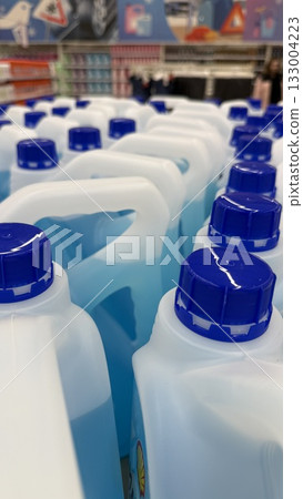 Blue plastic detergent bottles arranged on store shelf, focusing on caps and handles, vertical format Blue plastic detergent bottles arranged on store shelf, focusing on caps and handles, vertical format 133004223