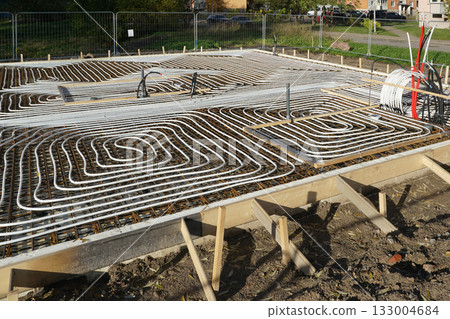 Underfloor heating pipes installed in concrete foundation during modern house construction project 133004684